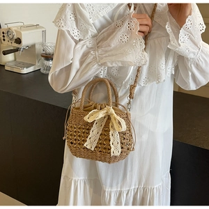 Détail du sac seau en paille tressée avec nœud en dentelle et doublure à cordon