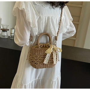 Détail d'un sac en paille tissé main avec motif évidé et décoration de nœud en dentelle