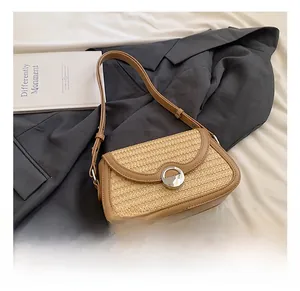 Détail du tissage en paille avec bordure en cuir et boucle en métal sur le sac d'épaule