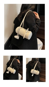 Detail of white cylinder bag with silver chain strap and a heart leather charm