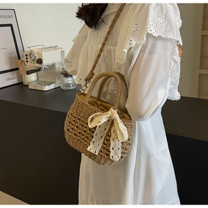 Détail du sac en paille avec nœud en dentelle blanche et chaîne dans un décor de café