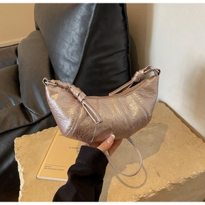 Détail du sac hobo violet métallisé avec texture plissée et bandoulière à nœuds élégante