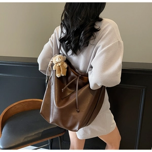 Detail of large brown soft leather tote bag with drawstring and cute bear charm