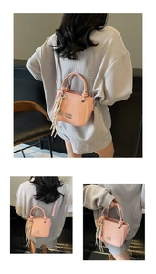 Detail der pinkfarbenen PU-Leder Eimertasche mit Metallbuchstaben und gestreiftem Seidenschal