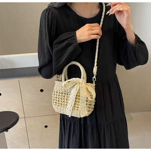 Détail du sac à bandoulière en paille avec nœud en dentelle et sangle tressée