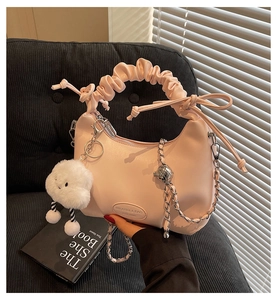 Close-up of pink ruched handbag with plush cloud charm and silver chain strap details