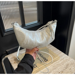 Gros plan du sac croissant argenté métallisé avec texture plissée et poignée à nœud élégante