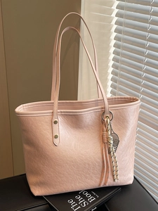 Pink lychee texture tote bag with tennis racket tassel shown in natural sunlight
