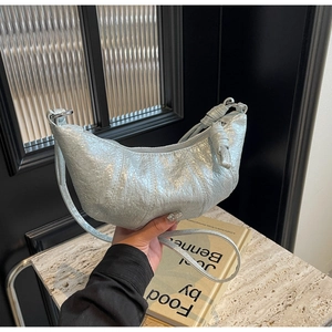 Vue détaillée du sac croissant argenté métallisé avec poignée nouée et coutures plissées
