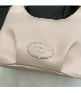 Close-up of pleated pink leather handbag featuring embossed brand logo and soft texture