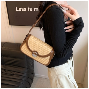 Détail du sac sous le bras en raphia avec bordure en cuir marron et boucle en métal