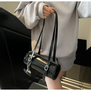 Detail of black glossy leather cylinder bag with silver hardware and heart charm