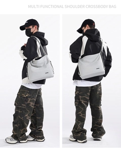Detail of light grey nylon tote bag showing adjustable straps and multi-way carrying styles