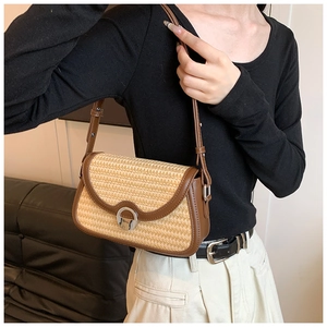 Détail du sac à bandoulière en paille avec bordure en cuir brun et boucle métallique