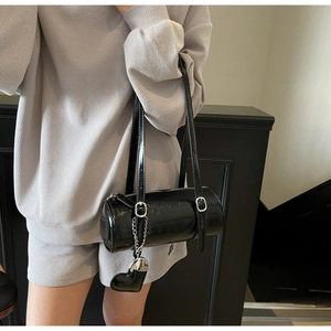 Detail of black wax leather barrel bag with silver hardware and heart charm decoration
