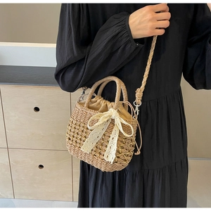 Détail d'un sac à main en paille avec nœud en dentelle, chaîne en métal et doublure à cordon