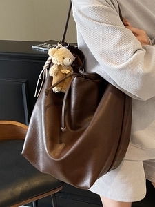 Minimalist deep brown large leather tote bag with a cute bear charm on a female model