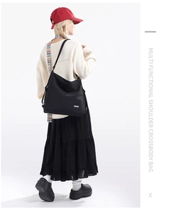 Close-up of black waterproof nylon tote bag showing side pockets and adjustable strap