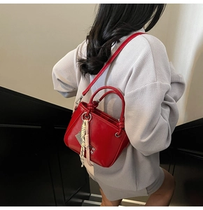 Rückansicht eines Models mit roter Lackleder-Beuteltasche und Quasten auf Treppen