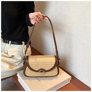 Détail d'un sac bandoulière en paille avec garniture en cuir brun et boucle métal