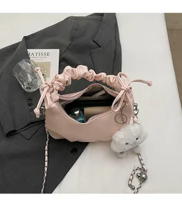 Detail view of pink pleated handbag interior with chain strap on a grey blazer