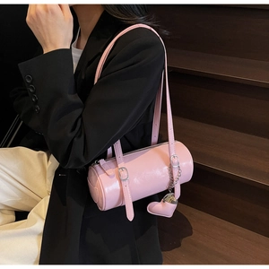Detailed view of pink cylindrical shoulder bag with heart pendant and silver chain strap