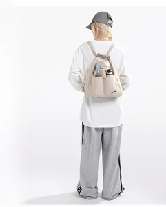 Detail of beige canvas tote bag with side pockets holding a water bottle and umbrella