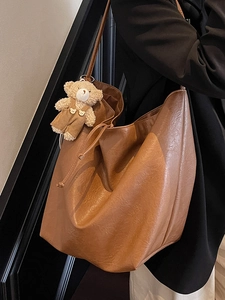 Brown faux leather tote bag with drawstring closure and cute teddy bear charm