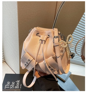 Détail du sac seau plissé rose avec œillets métalliques et breloque perle nœud
