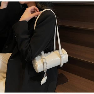 Close-up of cream oil wax leather cylinder bag with metal chain detail and strap
