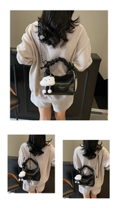 Close-up of black pleated faux leather bag with metal chain and plush cloud charm