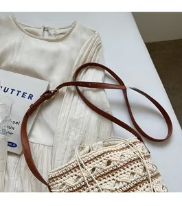 Detail of woven cotton bucket bag with adjustable brown leather strap and drawstring closure