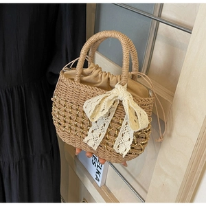 Détail du sac à main en paille avec nœud en dentelle blanche et chaîne dorée de vacances
