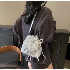 Détail du sac seau bleu clair plissé avec nœud en perles et ruban en dentelle fine