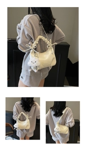 Detail of creamy white ruched handbag with plush cloud charm and metal chain strap