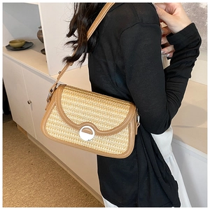 Détail d'un sac bandoulière en paille tressée avec bordure en cuir marron et fermoir argent