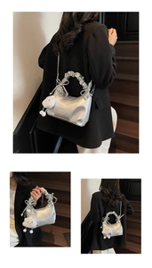 Detail of silver pleated handbag with bow, plush cloud charm, and metallic chain strap