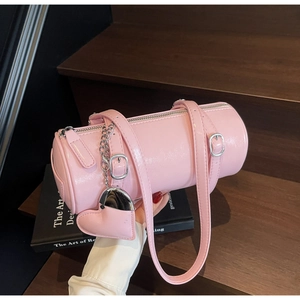 Detail of pink oil wax leather cylinder bag with heart charm and silver chain