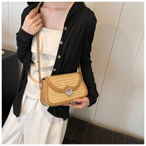 Détail du sac bandoulière en paille d'été avec bordure en cuir marron et boucle métal