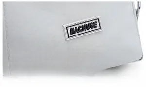 Detail of MACHUGE logo on grey tote bag with silver metal ring and twill texture