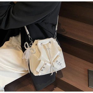 Détail du sac seau plissé blanc avec nœud en dentelle perlée et poches latérales