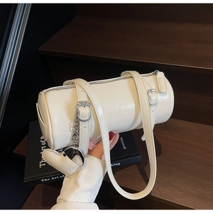 Close-up of cream oil wax leather cylinder bag with heart charm and silver hardware