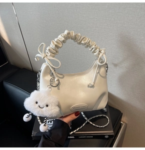 Detail of cream pleated handbag with silver chain strap and plush cloud charm