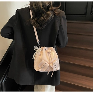 Sac seau rose avec breloque perle et nœud en dentelle porté en sac bandoulière
