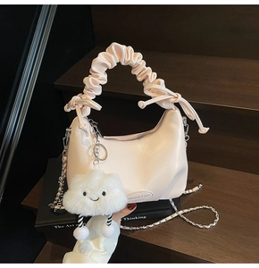 Close-up of pink pleated handbag featuring metal chain strap and cute cloud charm detail