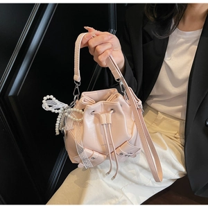 Détail du sac seau rose clair avec pendentif en perles et accessoire en dentelle