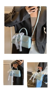 Detail of light blue square handbag with pearl chain, lace bow and silver metal lock