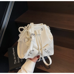 Détail d'un sac seau blanc plissé avec breloque nœud en perles et cordon de serrage