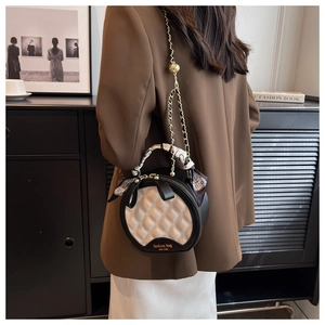 Détail du sac rond en cuir matelassé avec chaîne dorée et foulard en soie décoratif