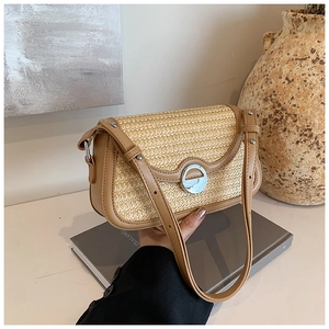 Détail d'un sac à bandoulière en paille tissée avec garniture en cuir brun et fermoir argent